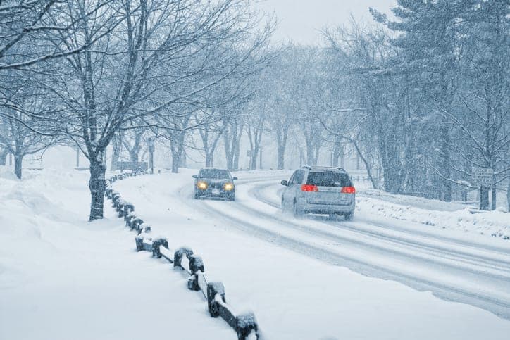 Minivan and passenger care safely driving on a snowy road.