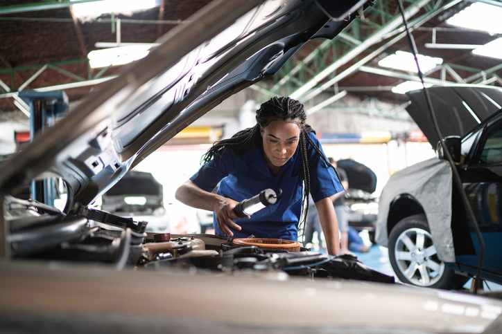Mechanic closely inspecting a car in a shop
