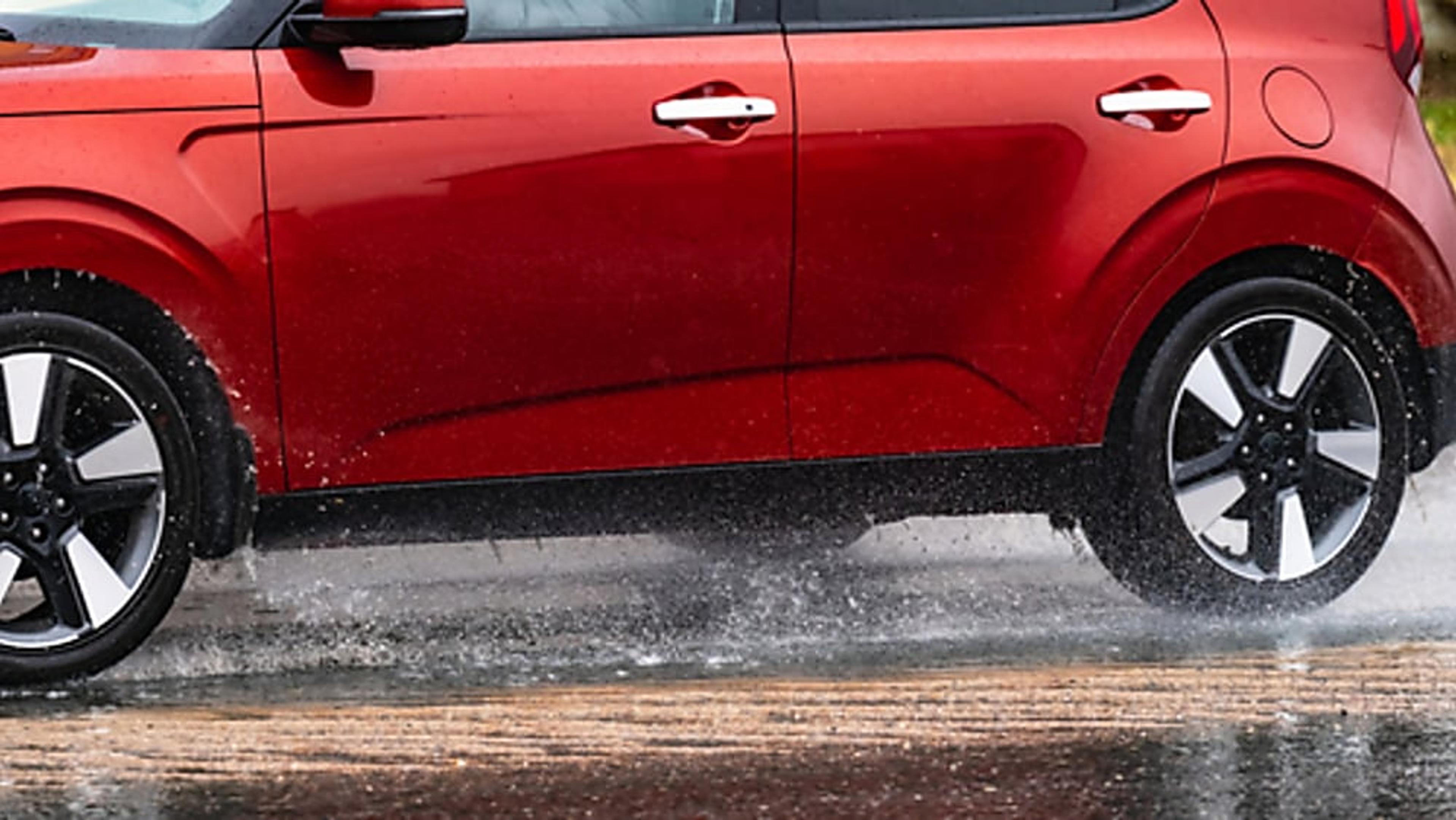 A red SUV driving on a wet road.