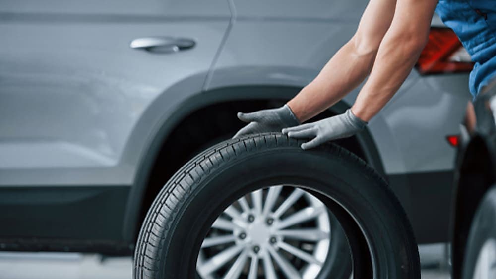 A mechanic rolling a new tire, preparing for the installation.